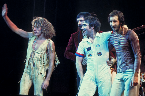 The Who on stage, standing and waving to a crowd. The Who, original line up, performing in Chicago. Left to right: Roger Daltrey, John Entwistle, Keith Moon, Pete Townshend.