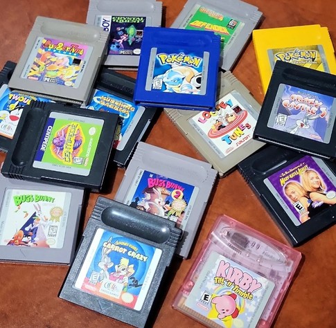 My collection of Game Boy games. 15 cartridges. Most gray, some black, one pink, one blue, one yellow. Pokemon, Looney Tunes, Centipede, BurgerTime, Crystal Quest, Kirby, etc. 