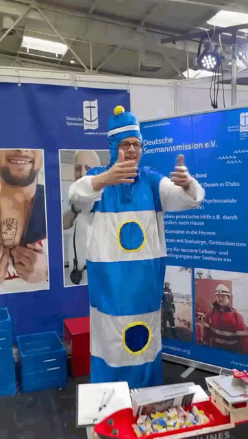 Wenn man im blau-weißen Leuchtturm Kostüm gestrig giert mit den Armen dahinter der Stand der Seemannsmission 