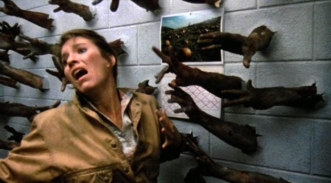 Zombie arms coming through the wall at a woman in Day of the Dead