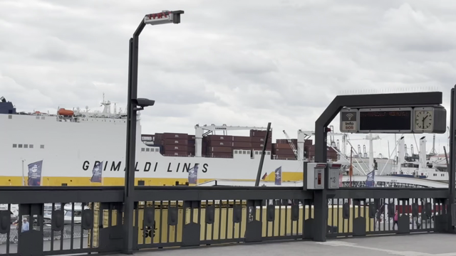 Über das Geländer vom U-Bahnhof hinweg sieht man ein großes Schiff, das gelb und weiß ist langsam die Elbe runterfährt