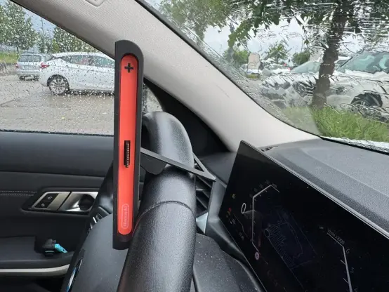 The Switch 2 with Mario Kart on it, but rested on the top of a car steering wheel, from the side